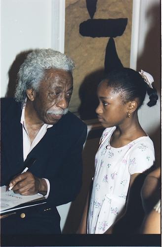 An older black man talks to a young black girl