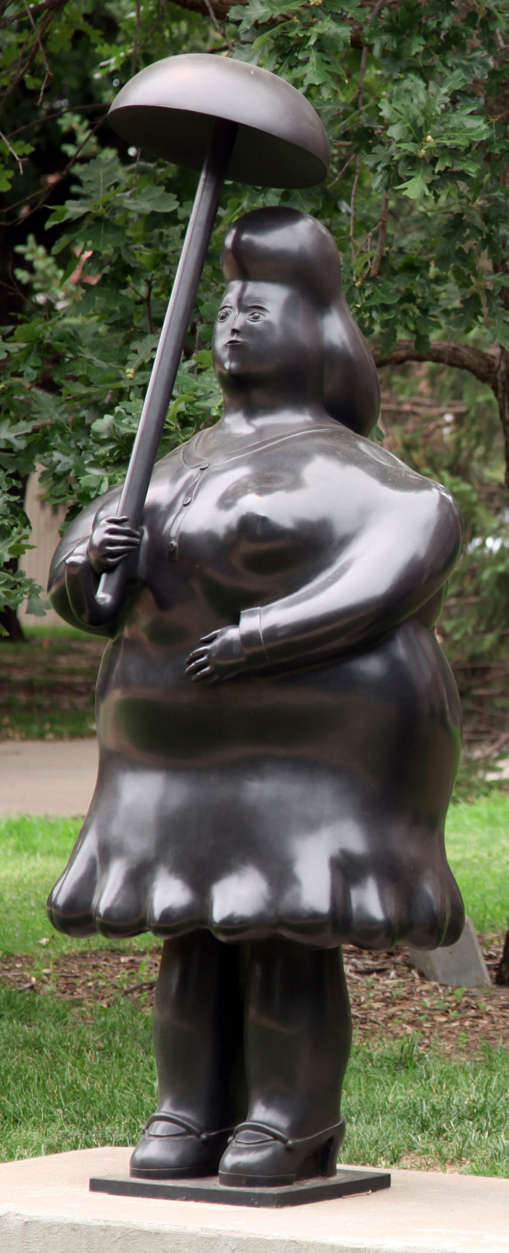 A large bronze statue of a woman with an umbrella stylized with rounded features