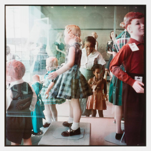 a Black girl with her grandma looks at white dolls in a 1950s shop window