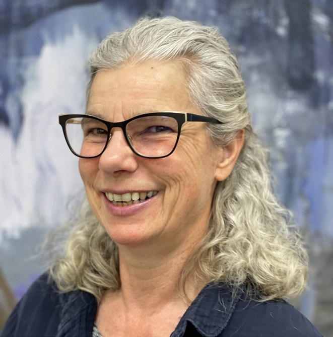 A woman wearing glasses and smiling at the camera