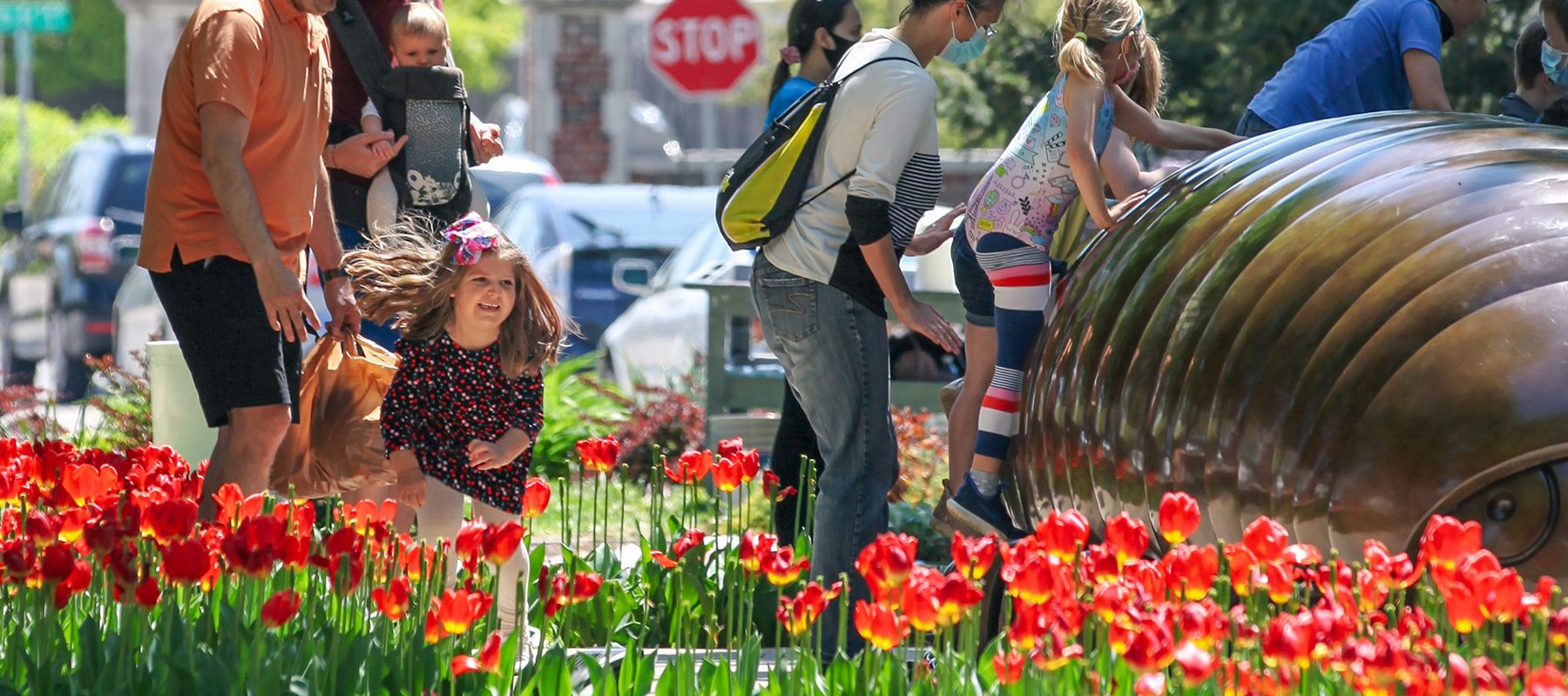 Family enjoying an outdoor sculpture surrounded by tulips at Ulrich Family Fun Day