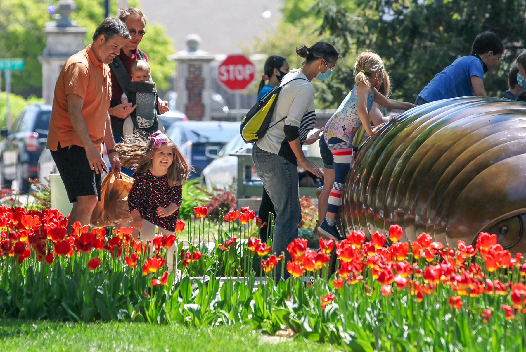 Family enjoying an outdoor sculpture surrounded by tulips at Ulrich Family Fun Day