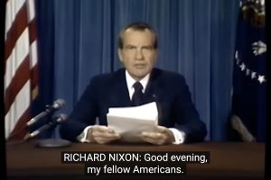 Late American president Richard Nixon is at a desk speaking to the public. TEXT: RICHARD NIXON: Good Evening, my fellow Americans.