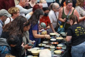 A crowd of attendees gather around a table to choose their handmade bowl at the Empty Bowls Chili Cook-Off in 2022.