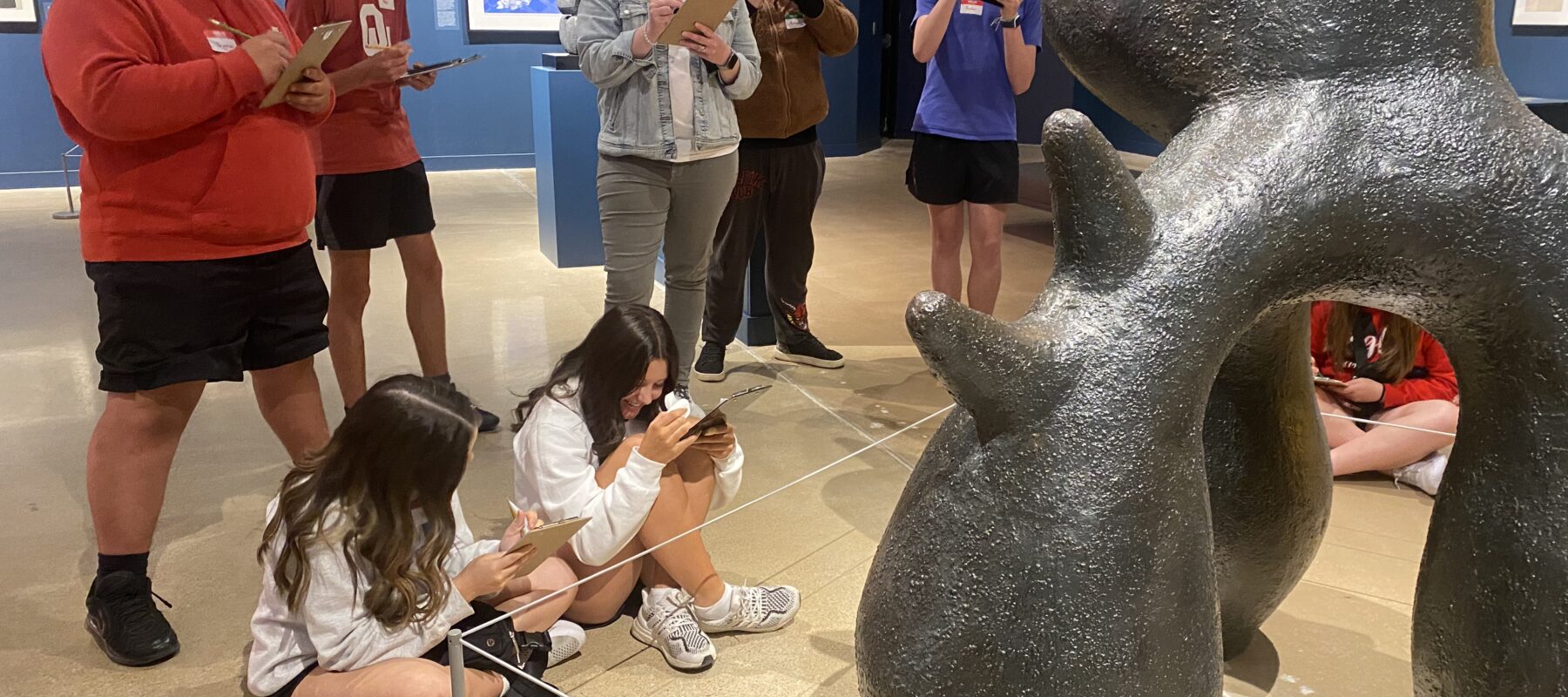A group pf students sketch a sculpture in a gallery.