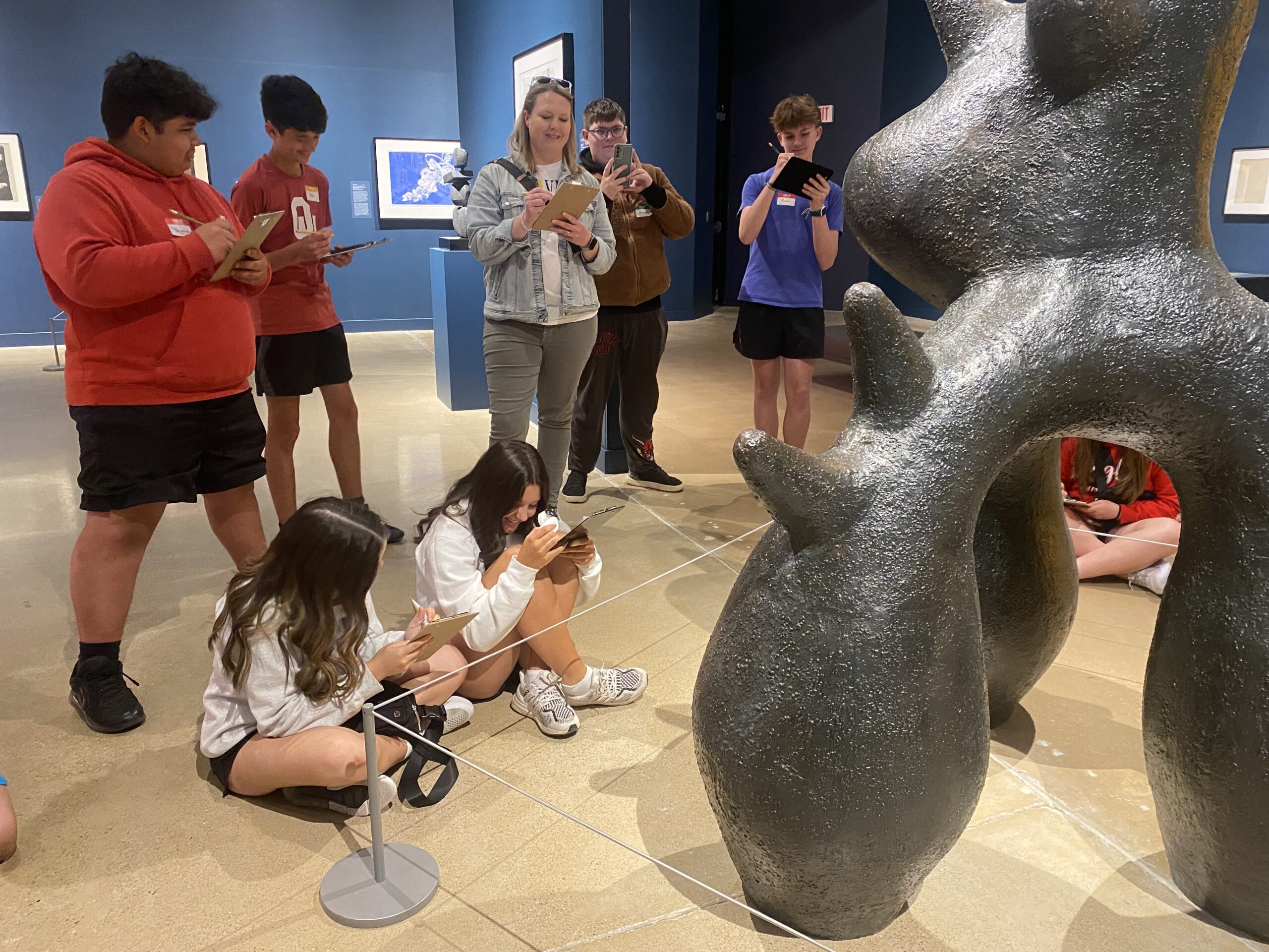 A group pf students sketch a sculpture in a gallery.