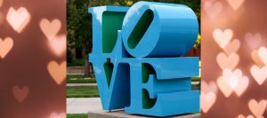 Robert Indiana's turquoise and green sculpture Love is placed on a background of pink hearts.