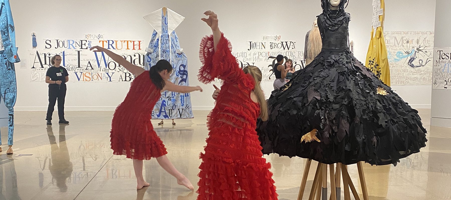 Dancers perform around artwork in a gallery.