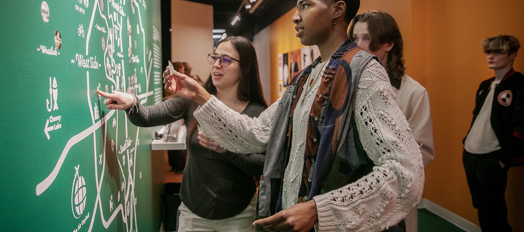 Young people chat and place stickers on a wall map.