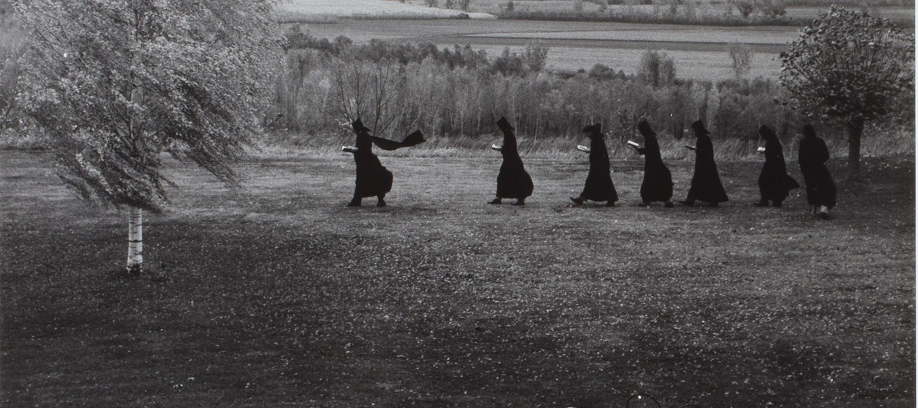 Witches run across a field.