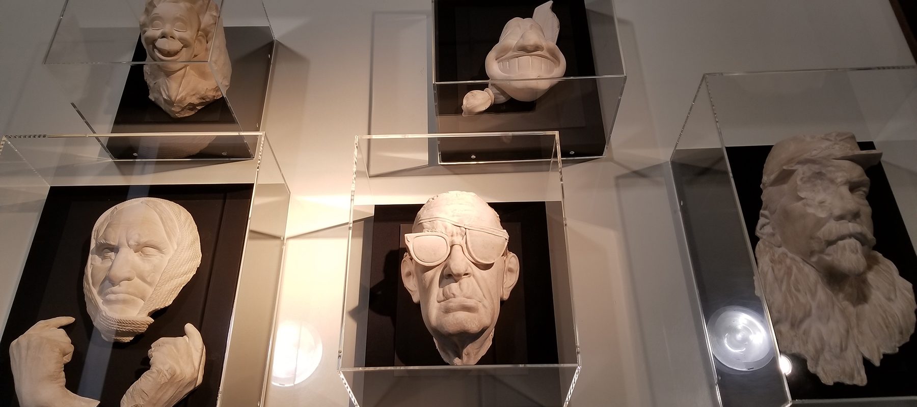 Five white death masks lie in a case.