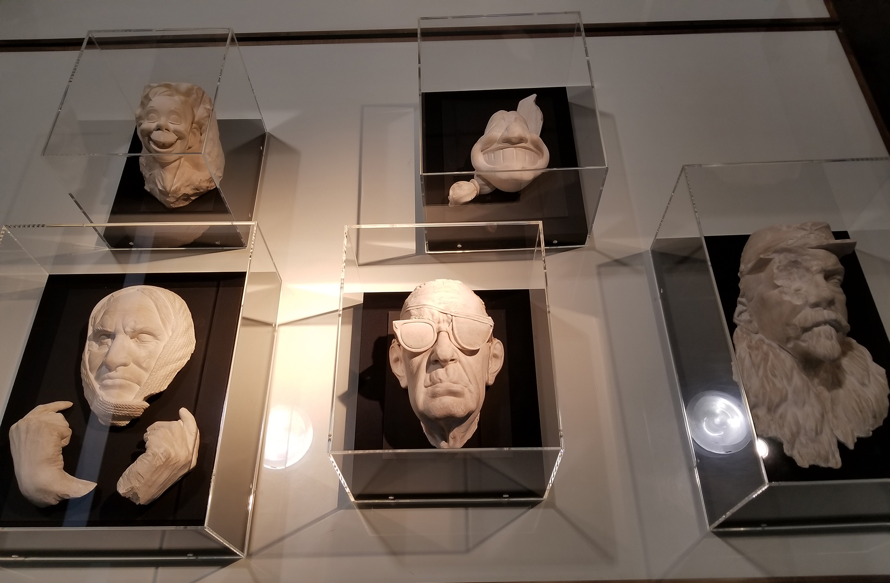 Five white death masks lie in a case.