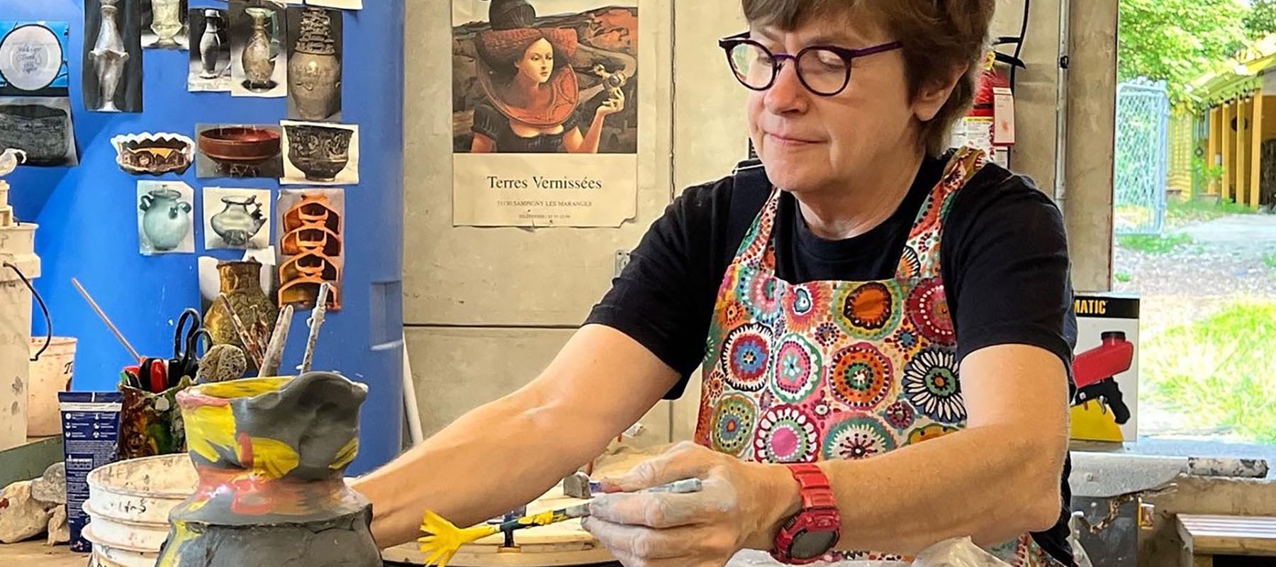 A woman is sculpting a stoneware pot.