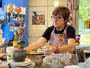 A woman is sculpting a stoneware pot.