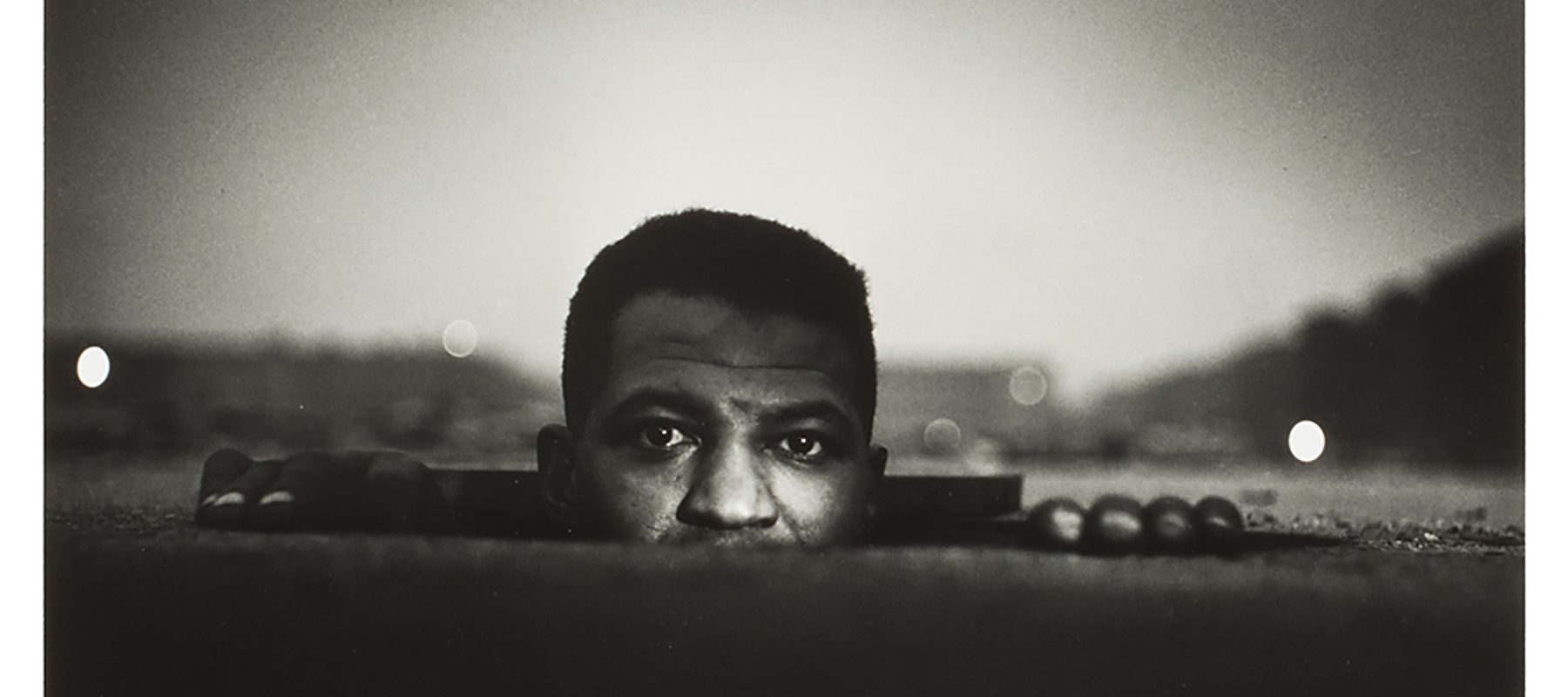 Black and white photo of a man rising out of a hole in the ground.