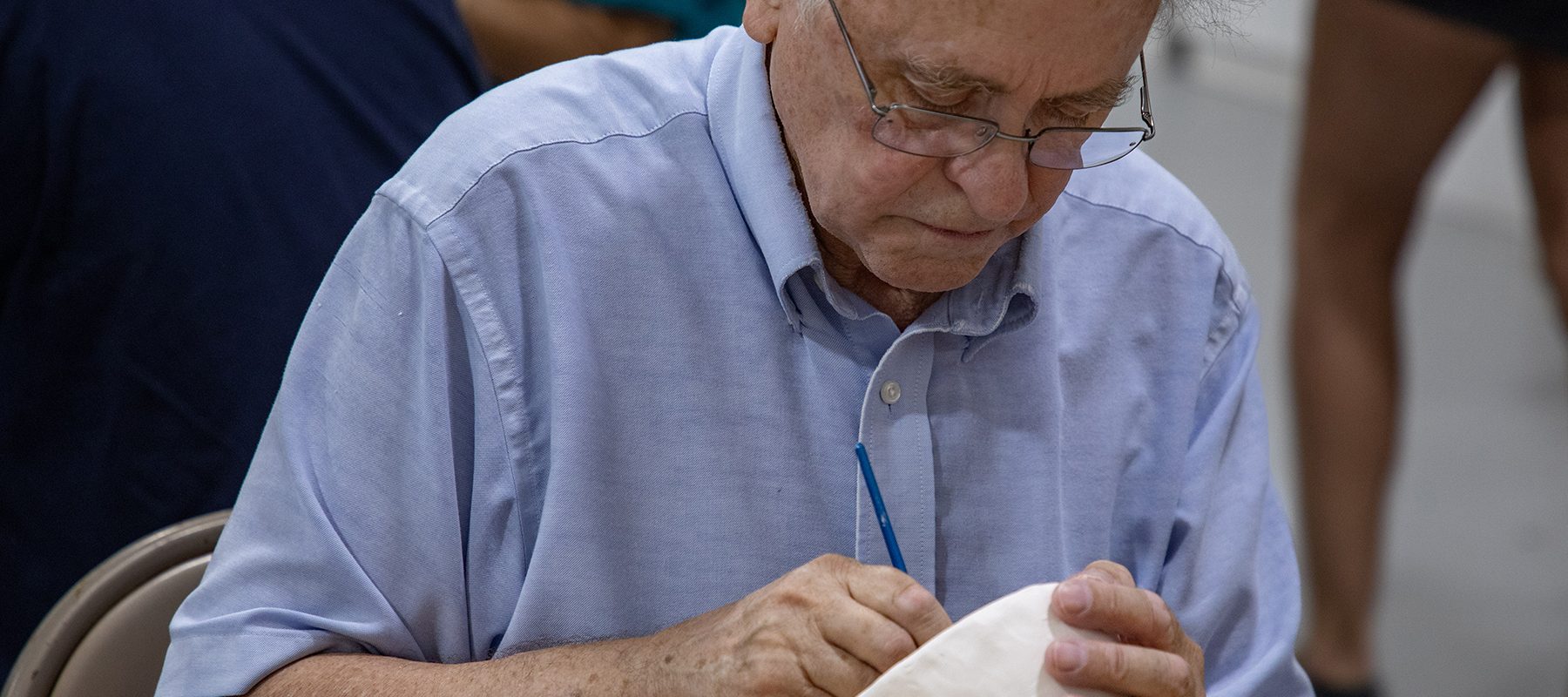 An senior man sculpts a bowl.