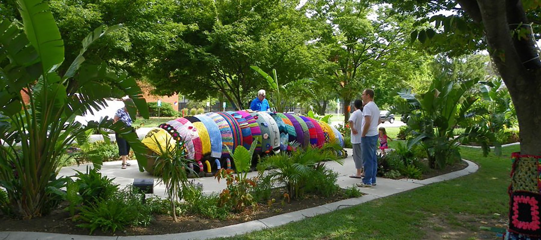 Visitors look at a bronze millipede statue covered with colorful fiber handwork.