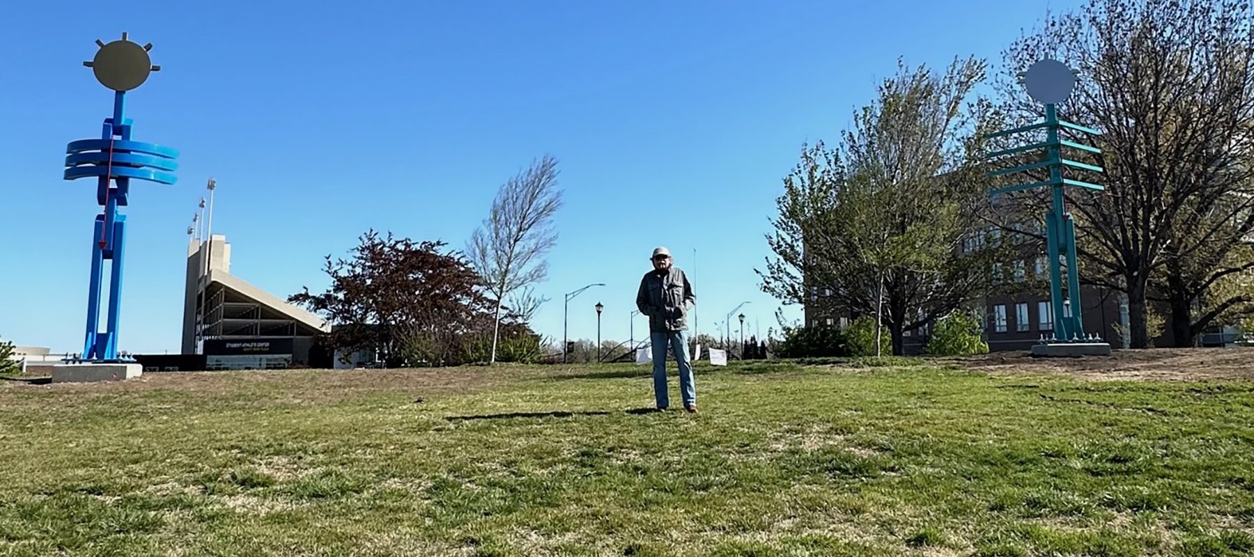 A man stands between two tall sculptures.