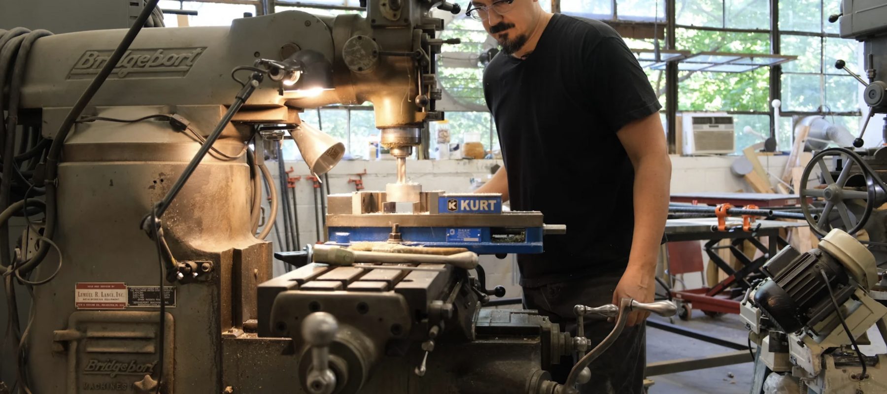 A man with a mustache works in an art studio.