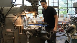 A man with a mustache works in an art studio.