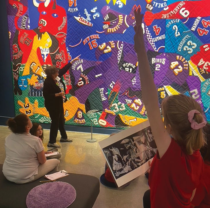 A young girl raises her hand to ask a question posed by a volunteer