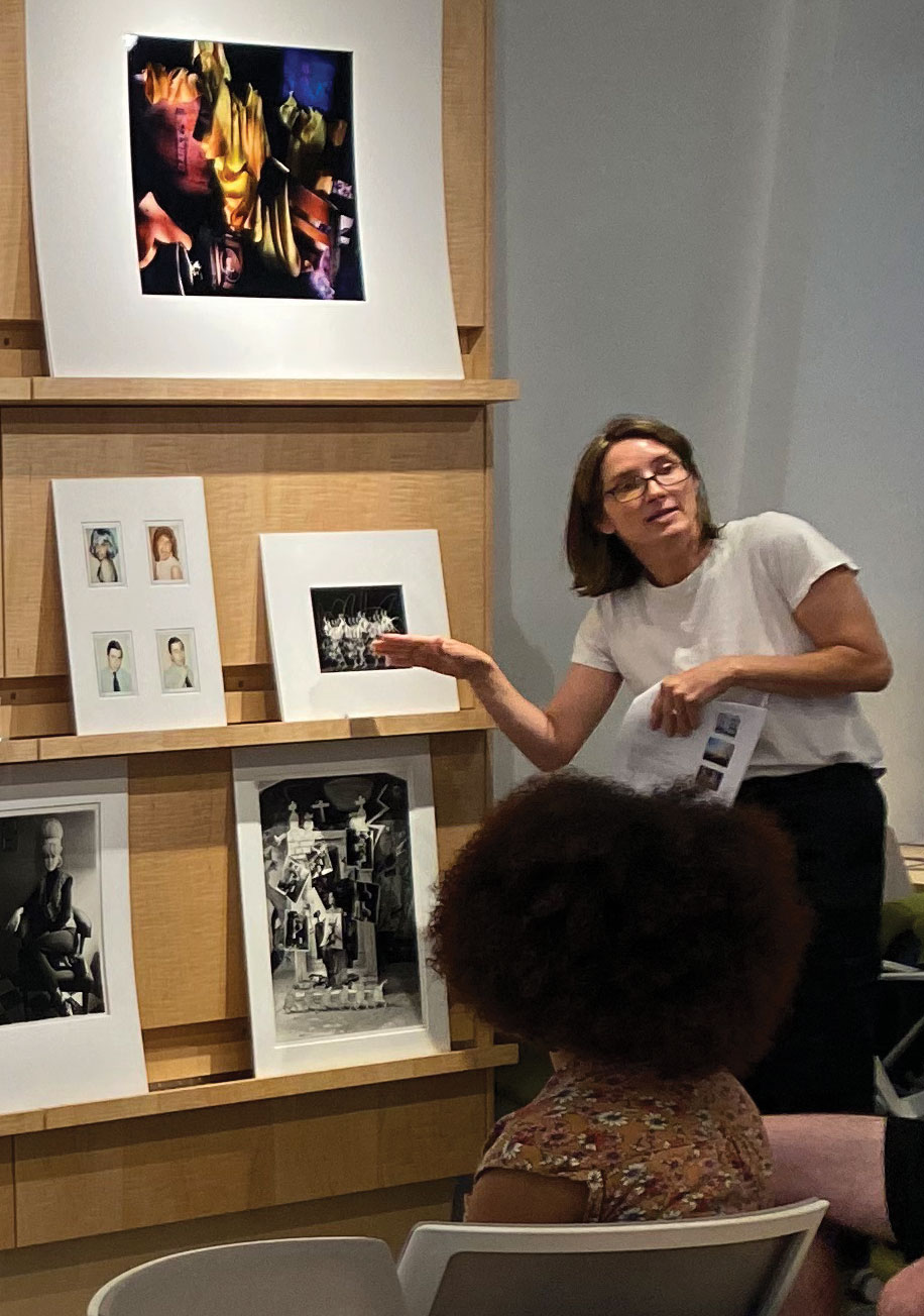 A woman points out art on a display behind her