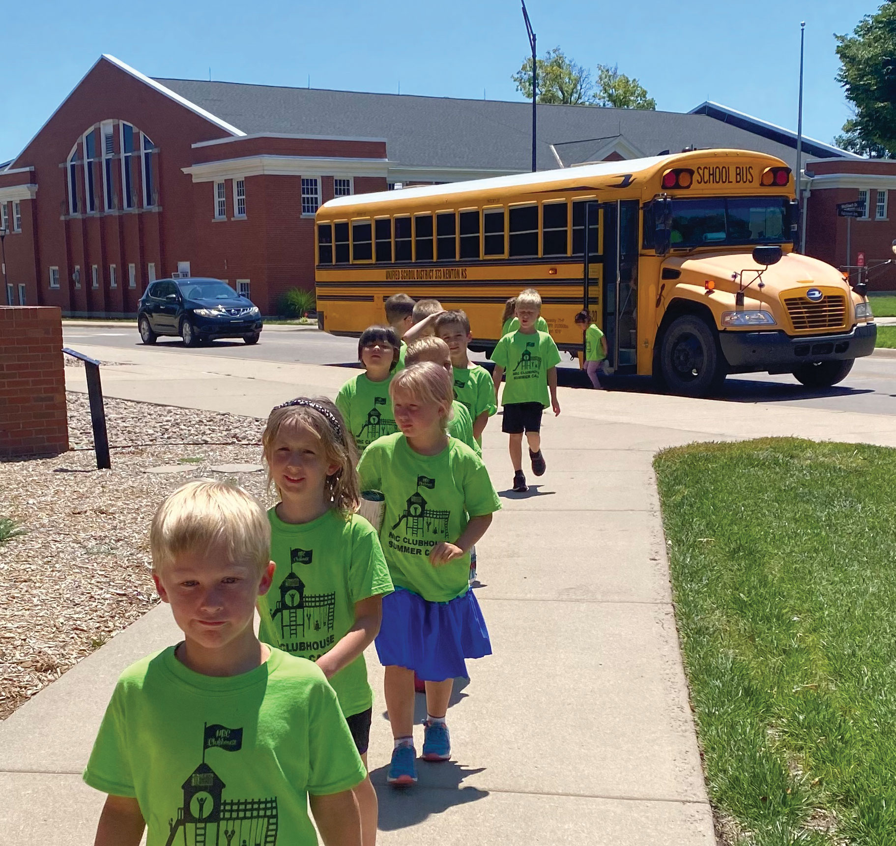 A group of children walk from a school bus towards the ulrich museum