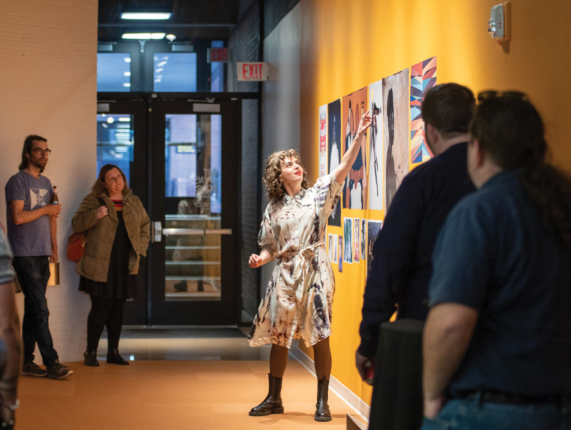 Vivian Zavataro, Executive and Creative Director, points out a detail on a painting for a gathered crowd