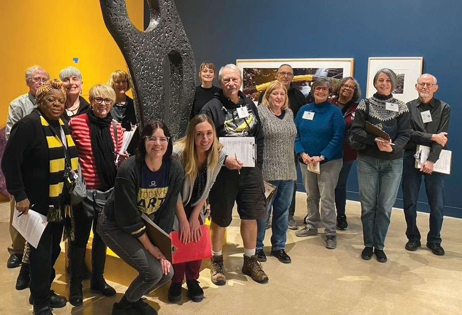 15 museum docents and a curator pose for a group photo