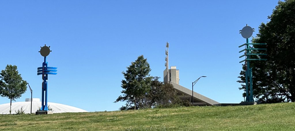 Two totem sculptures stand in a field.