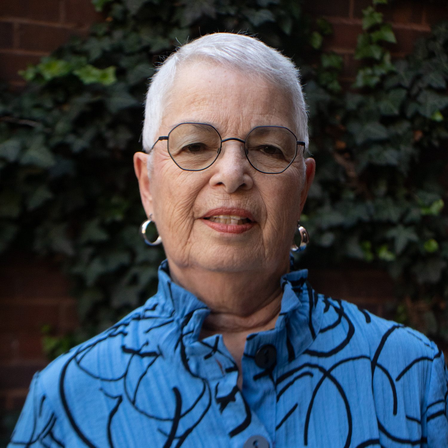 A smiling woman with glasses in a blue shirt