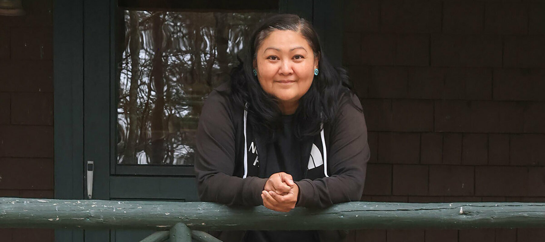 A smiling woman leans on a railing.