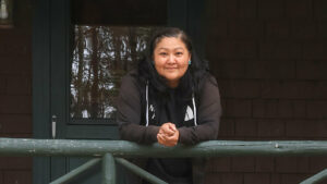 A smiling woman leans on a railing.