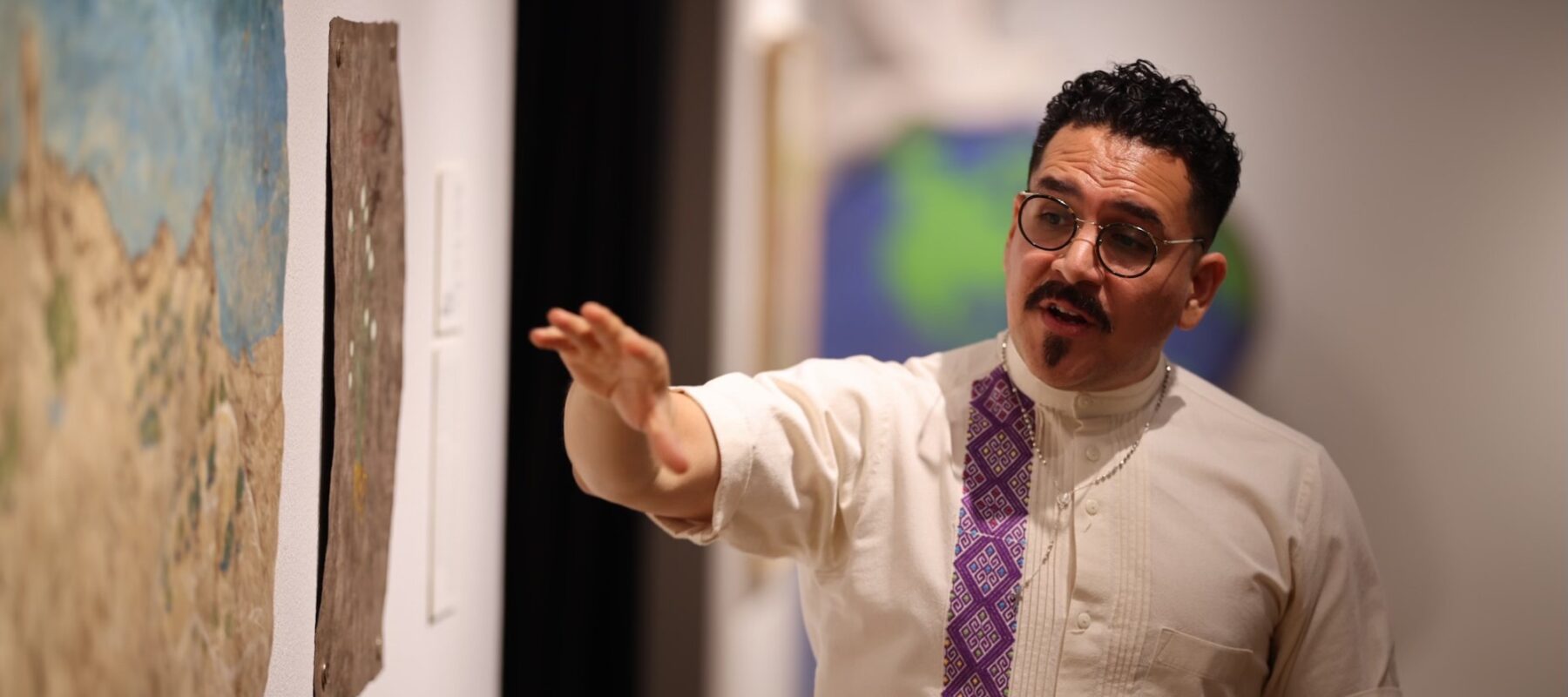 A man indicates an area in an artwork as he lectures.