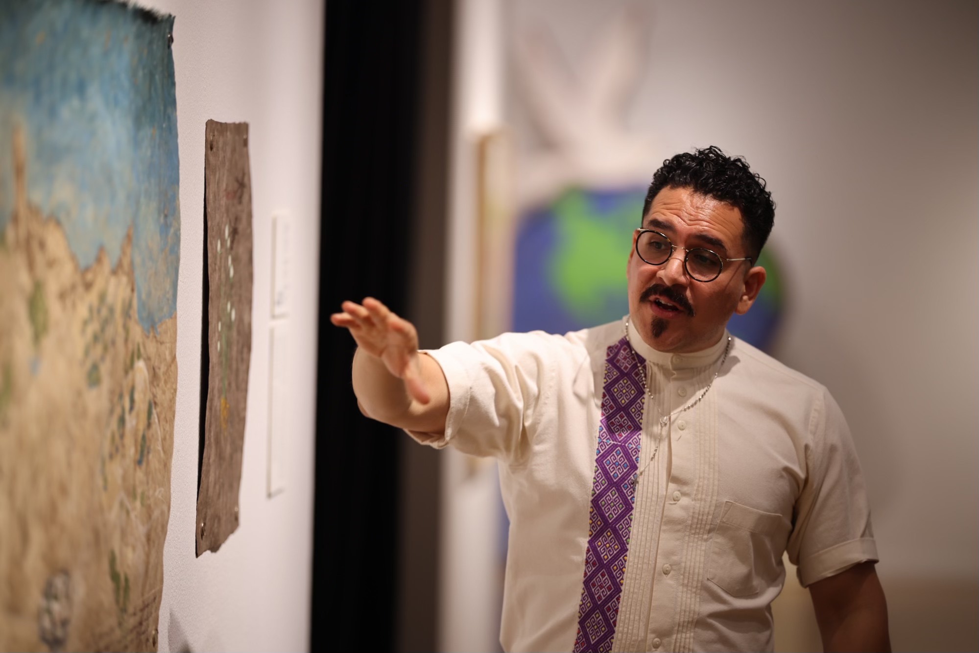 A man indicates an area in an artwork as he lectures.