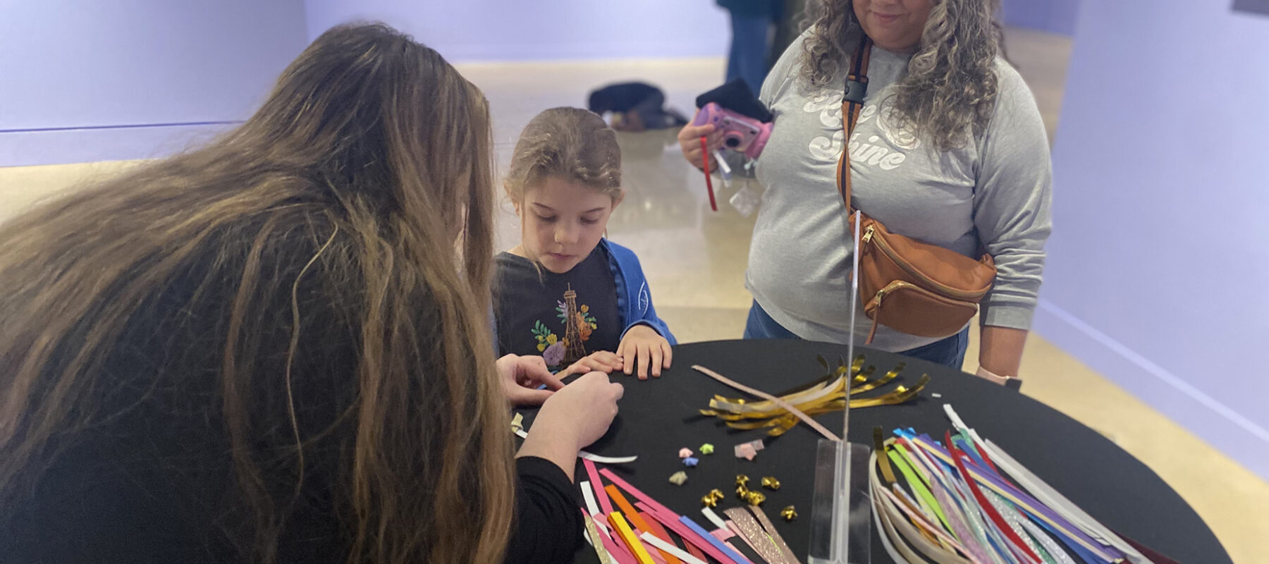 A child does an art project while a grown-up looks on.
