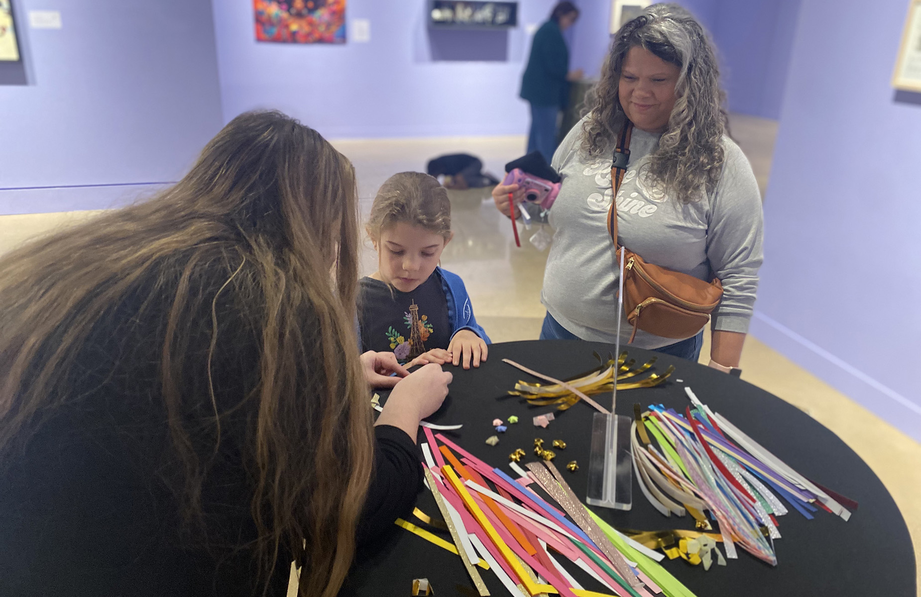 A child does an art project while a grown-up looks on.