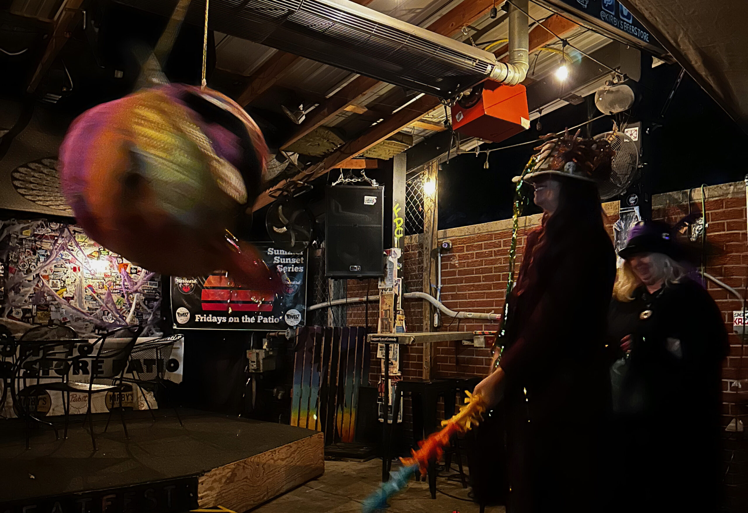 Two ladies in costume hit a pinata