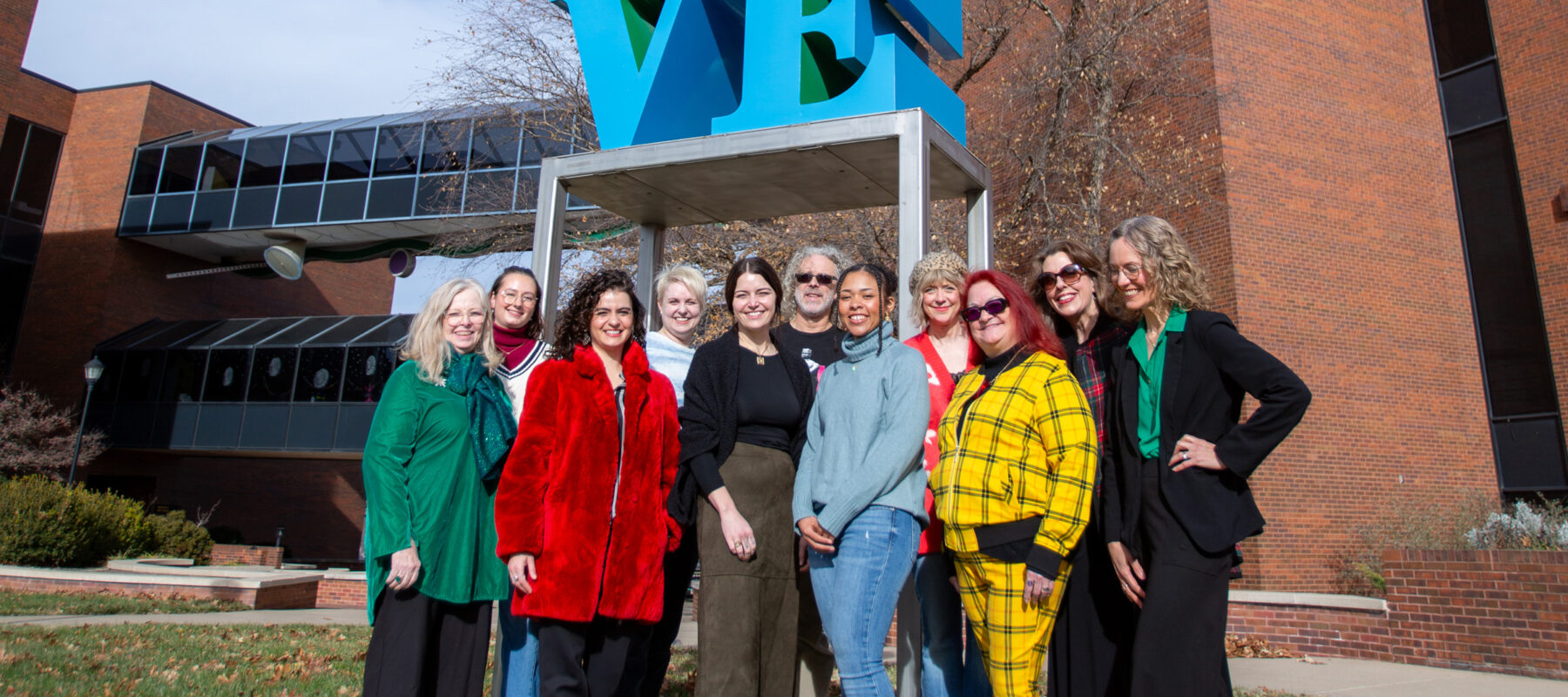 A group of people posed playfully in front of a sculpture.