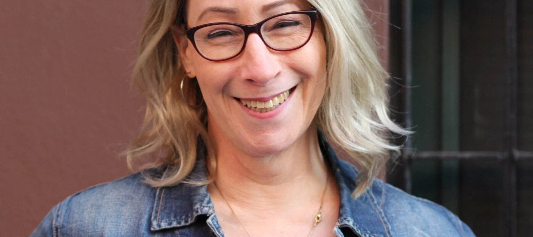 A smiling blond woman in a jean jacket