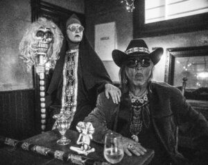 The Artist Guillermo Gomez-Pena and wife pose together in a dark room.