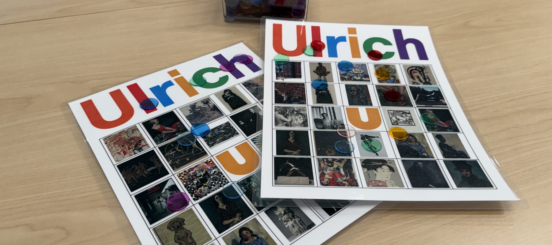 Two Ulrich branded Bingo cards and a container of tiddlywinks on a table.